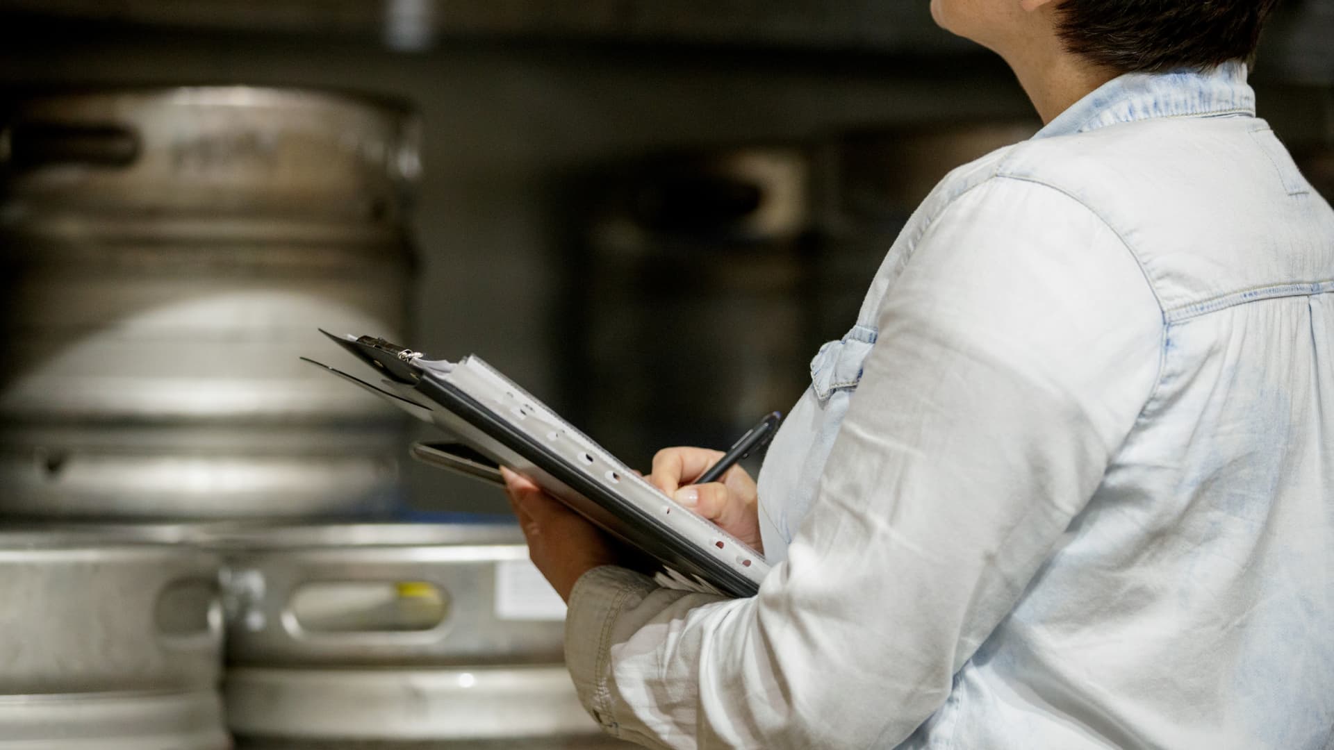 An employee inspects kegs on a keg rack in a foodservice operation. 