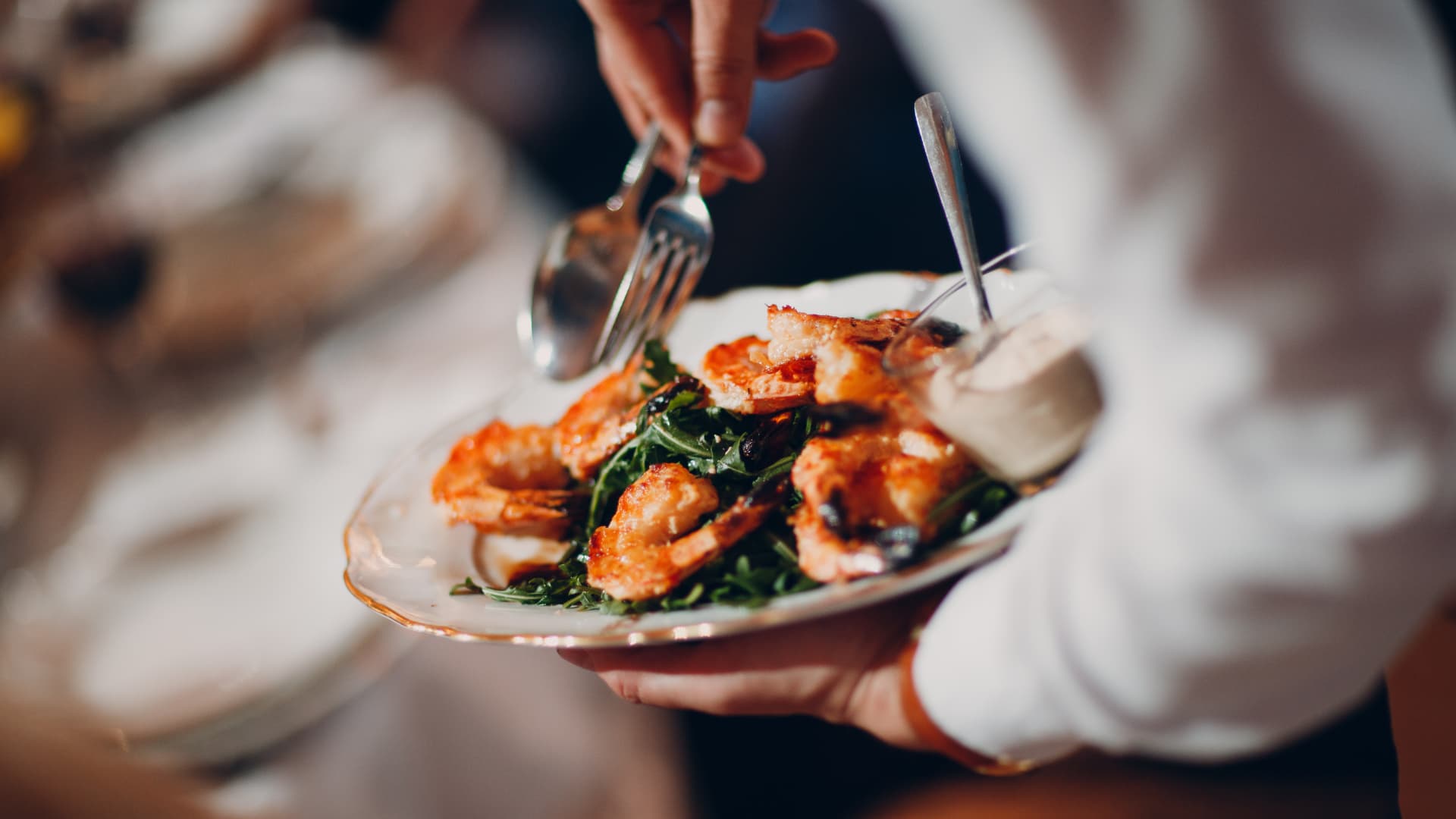 An image of fresh food being served by a waiter in a restuarant.